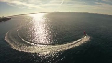 Bir adam Noel Baba kostüm jetsurf üzerinde güzel okyanus kıyısı havadan görünümü sürmek.