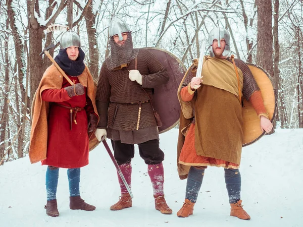 Skupina ozbrojených bojovníků s štíty, meče, kopí v zimním lese — Stock fotografie