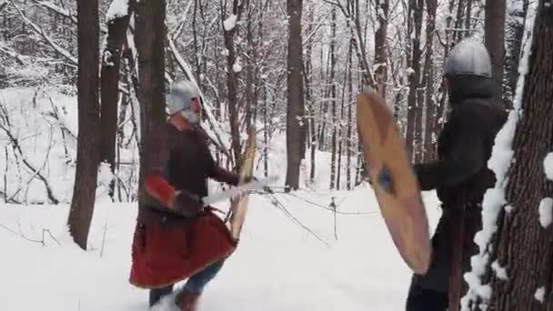 Guerreros irlandeses y vikingos medievales en armadura luchando en un bosque de invierno con espadas y escudos — Vídeo de stock