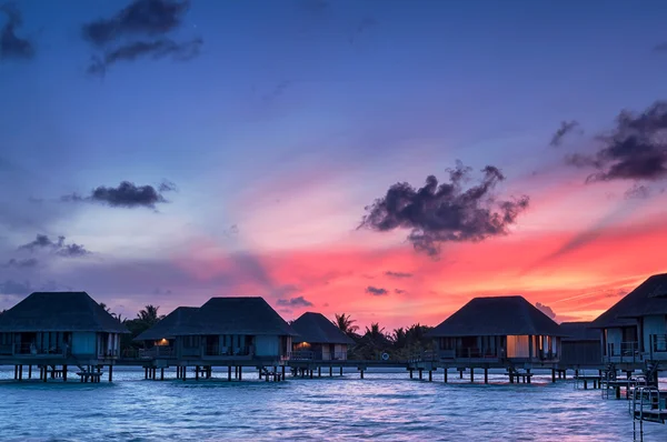 Salida del sol sobre bungalows de agua en Maldivas — Foto de Stock