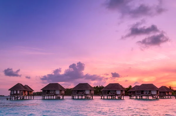 Salida del sol sobre bungalows de agua en Maldivas — Foto de Stock