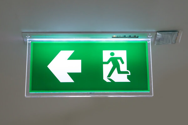 green emergency exit sign showing the way to escape