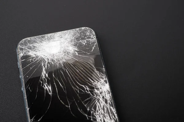 Smartphone com tela quebrada no fundo escuro — Fotografia de Stock