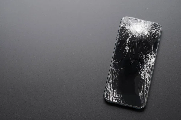Smartphone com tela quebrada no fundo escuro — Fotografia de Stock