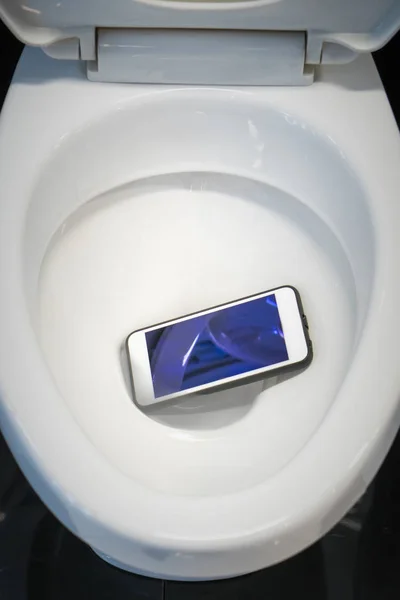 Uno smartphone bianco caduto in una tazza del water . — Foto Stock