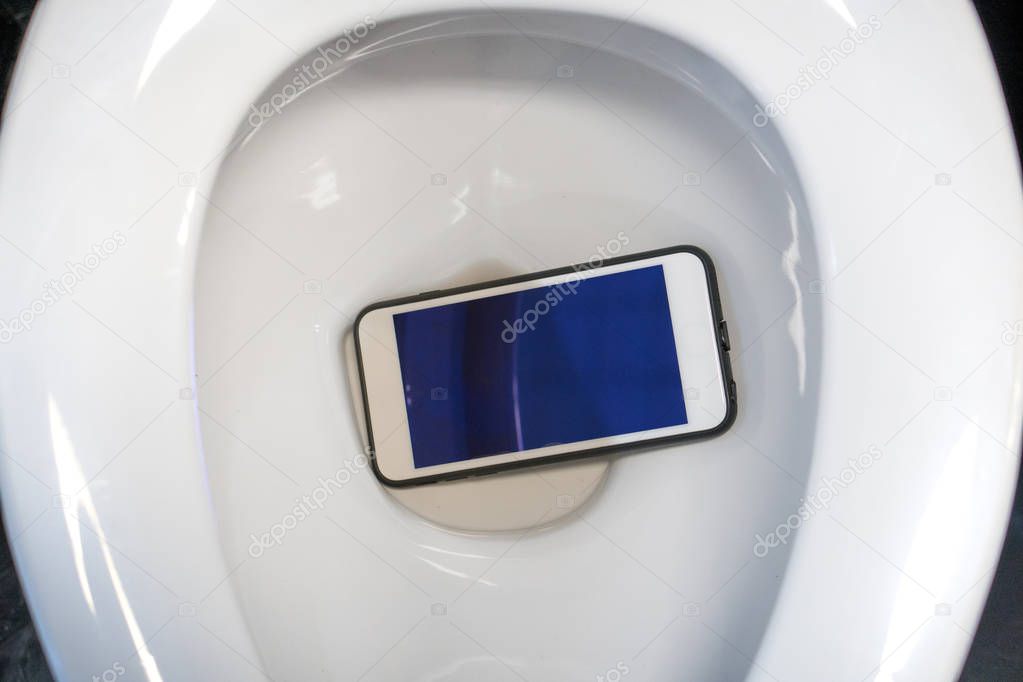 A white smartphone dropped into a toilet bowl.