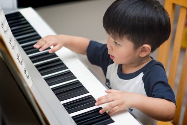 Asya evde piyano çalan çocuk.