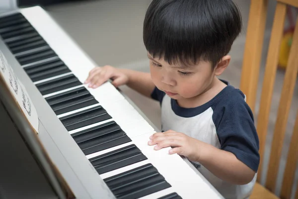 Asya evde piyano çalan çocuk.