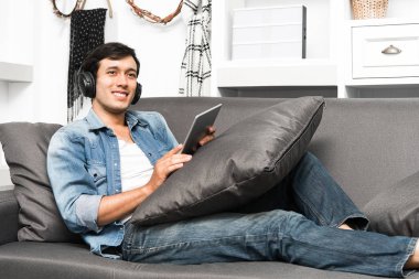 Yakışıklı olan kulaklık ile kanepede oturan.