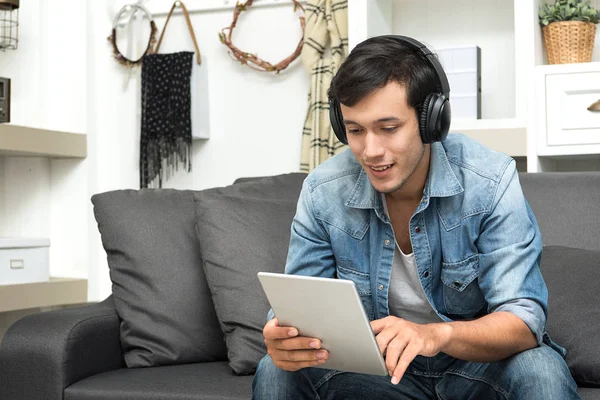 Handsome guy sitting on sofa with headphones.
