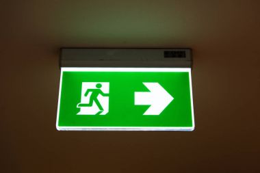 Kaçış yolunu gösteren yeşil acil çıkış işareti.