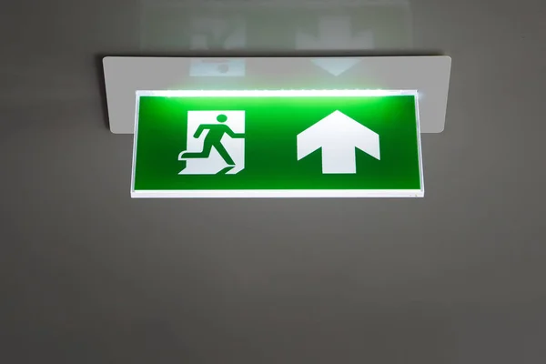 Зеленый знак аварийного выхода, указывающий путь эвакуации . — стоковое фото