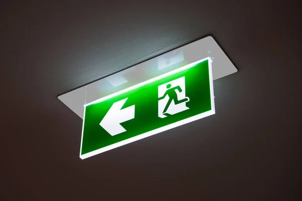 green emergency exit sign showing the way to escape.