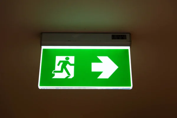 green emergency exit sign showing the way to escape.