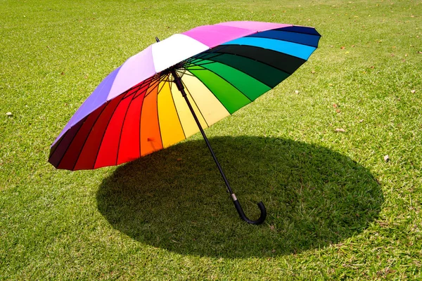 Rainbow umbrella in grass field vintage and retro tone, soft foc — Stock Photo, Image