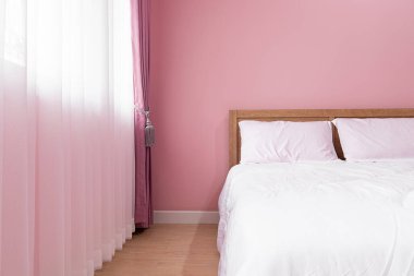 Yatak odası. Pembe duvarın yanında rahat bir yatak odası.