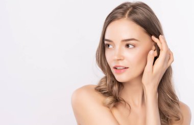 Güzel, genç bir kadın temiz yüzüne dokunuyor. Sağlıklı cilt, beyaz arka planda izole edilmiş güzellik kozmetik ve yüz bakımı konsepti..