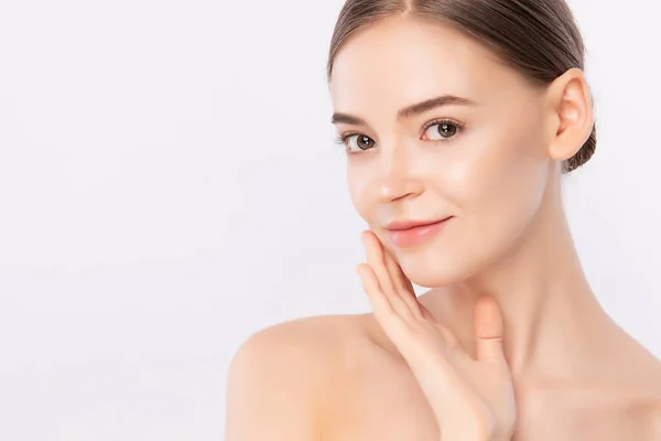 Güzel, genç bir kadın temiz yüzüne dokunuyor. Sağlıklı cilt, beyaz arka planda izole edilmiş güzellik kozmetik ve yüz bakımı konsepti..