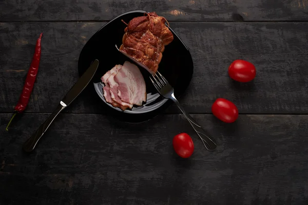 Bacon sur une assiette noire sur une table en bois — Photo