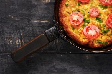 ahşap masa üzerinde domates ile bir tavada yumurta omlet