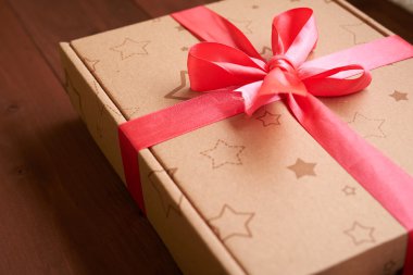 ahşap bir masa üzerinde pembe bir kurdele ile hediye paketi