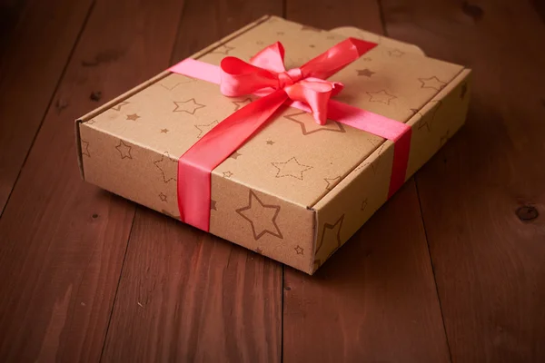 Envoltura de regalo con una cinta rosa en una mesa de madera — Foto de Stock