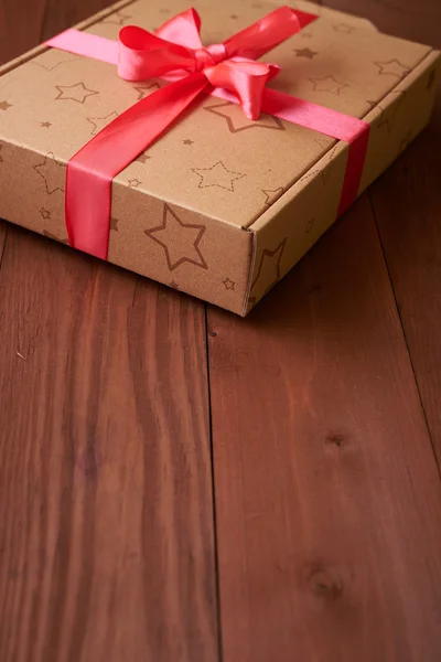 Incarto regalo con un nastro rosa su un tavolo di legno — Foto Stock
