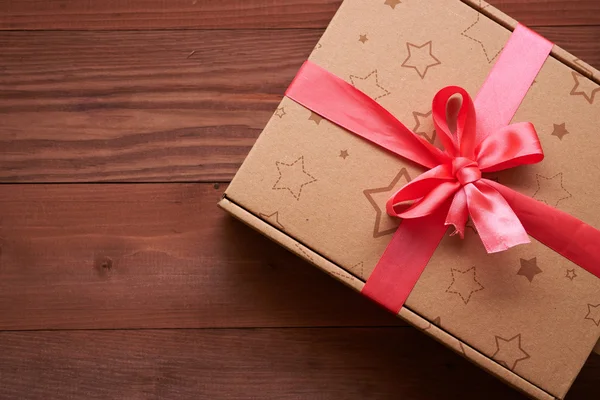 Gift wrap met een roze lint op een houten tafel — Stockfoto