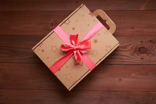 Envoltura de regalo con una cinta rosa en una mesa de madera — Foto de Stock