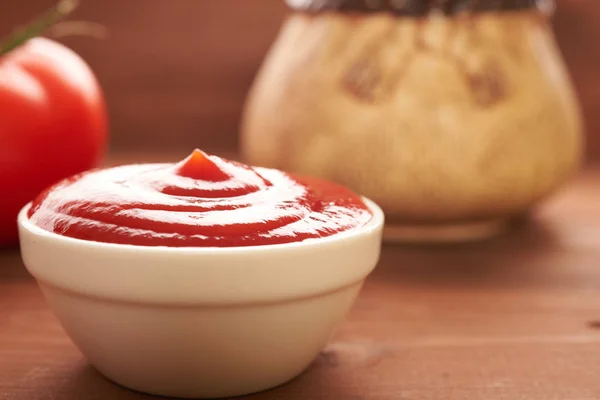 Ketchup i pomidorów na drewnianym stole — Zdjęcie stockowe