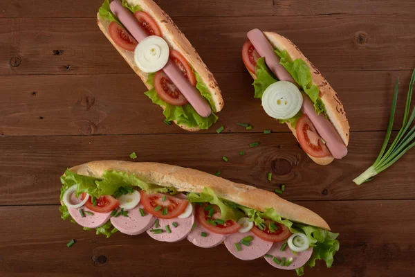 Sandwich aux saucisses et légumes sur une table en bois — Photo