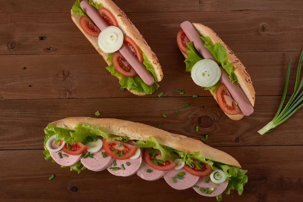 Panino con salsiccia e verdure su un tavolo di legno — Foto Stock