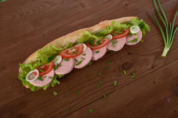 Emparedado con salchichas y verduras en una mesa de madera — Foto de Stock