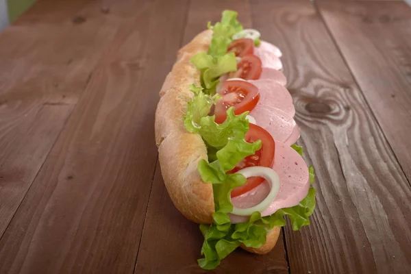 Panino con salsiccia e verdure su un tavolo di legno — Foto Stock