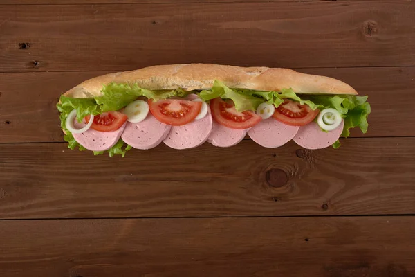 Emparedado con salchichas y verduras en una mesa de madera — Foto de Stock