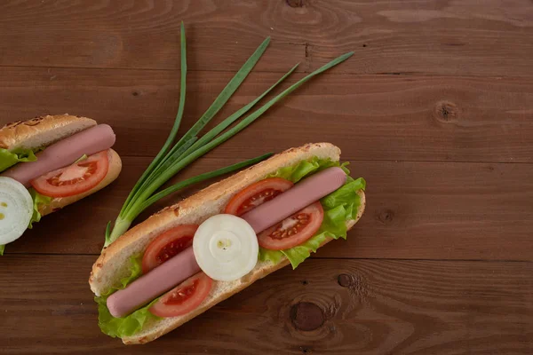 Бутерброд з сосискою та овочами на дерев'яному столі — стокове фото