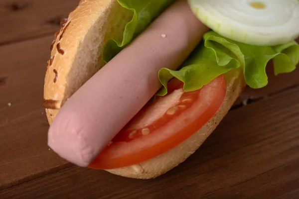 Panino con salsiccia e verdure su un tavolo di legno — Foto Stock