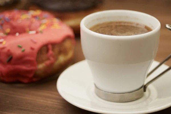 Пончики и кофе на деревянном столе — стоковое фото
