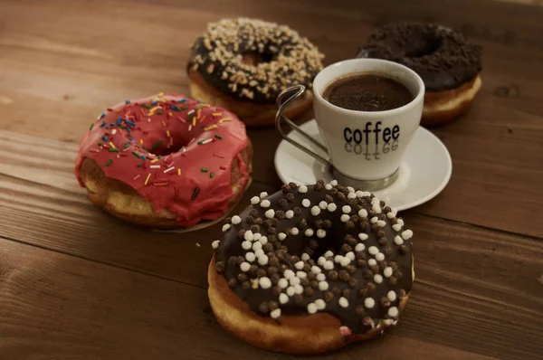 Пончики и кофе на деревянном столе — стоковое фото