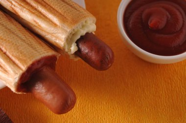 Sarı bir arka plan üzerinde iki sosisli sandviç