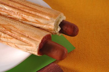 Sarı bir arka plan üzerinde iki sosisli sandviç