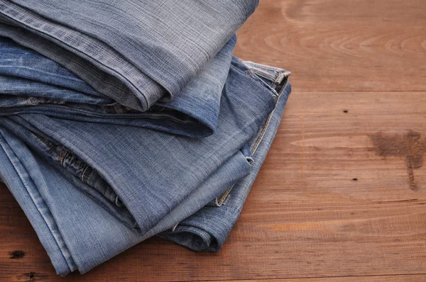 Pila de jeans sobre un fondo de madera — Foto de Stock