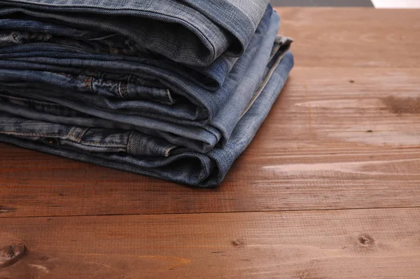 Pila de jeans sobre un fondo de madera — Foto de Stock