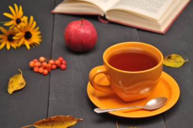 Sonbahar natürmort fincan çay, çiçekler ve kitap masada