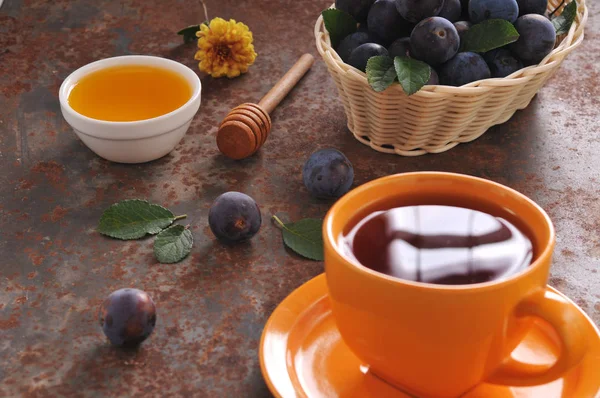 Чашка чая и сливы на столе — стоковое фото
