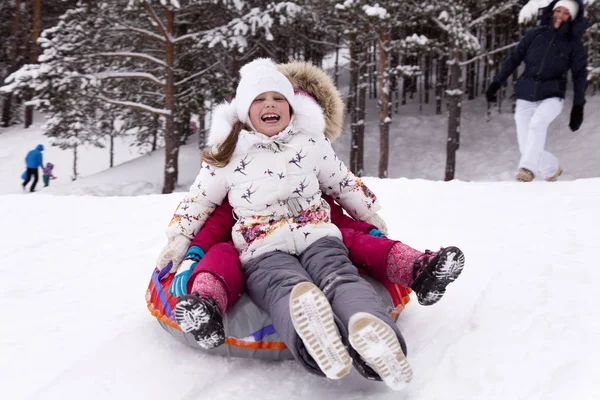 Šťastná holčička křičí rozkoší, válcování s snow hill. — Stock fotografie