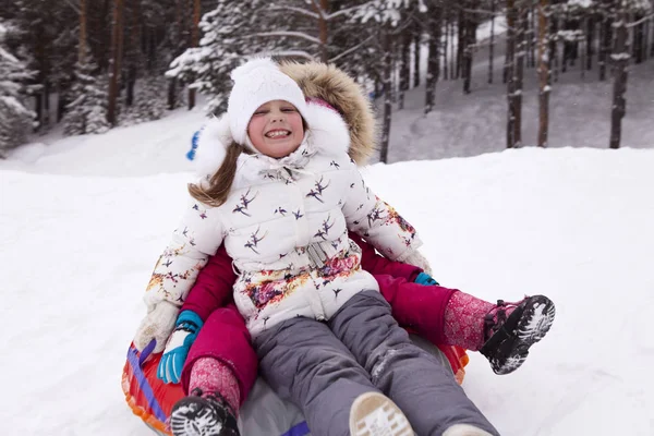 Šťastná holčička křičí rozkoší, válcování s snow hill. — Stock fotografie