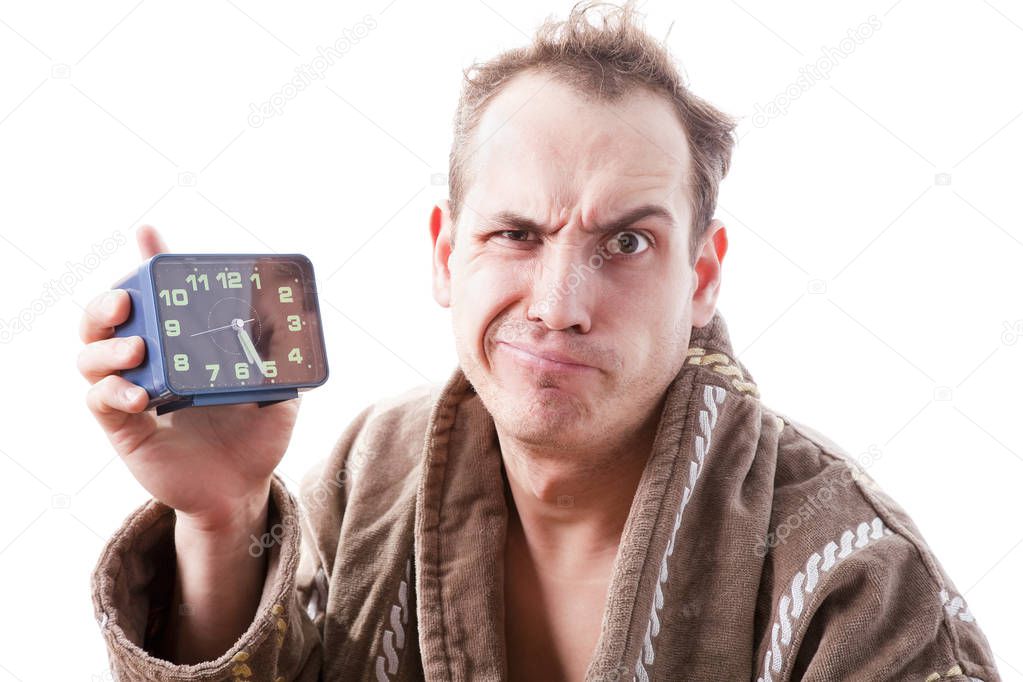 sleepy disgruntled man with alarm clock in hand early in the mor