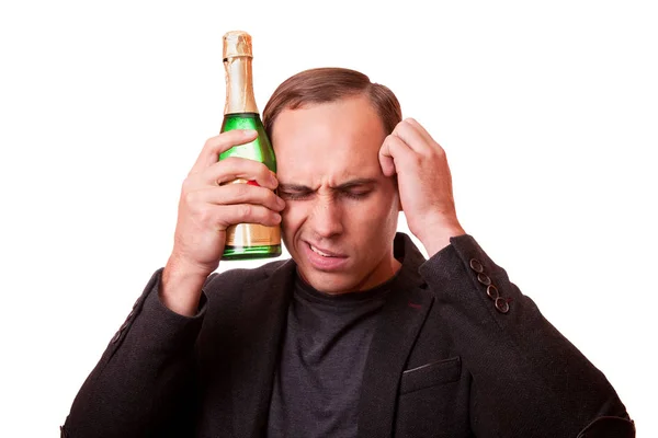 Ung man lider av en baksmälla med en flaska champagne i — Stockfoto