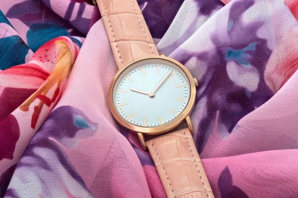 Renkli ipek kumaş arka plan üzerinde pembe kol saati — Stok fotoğraf